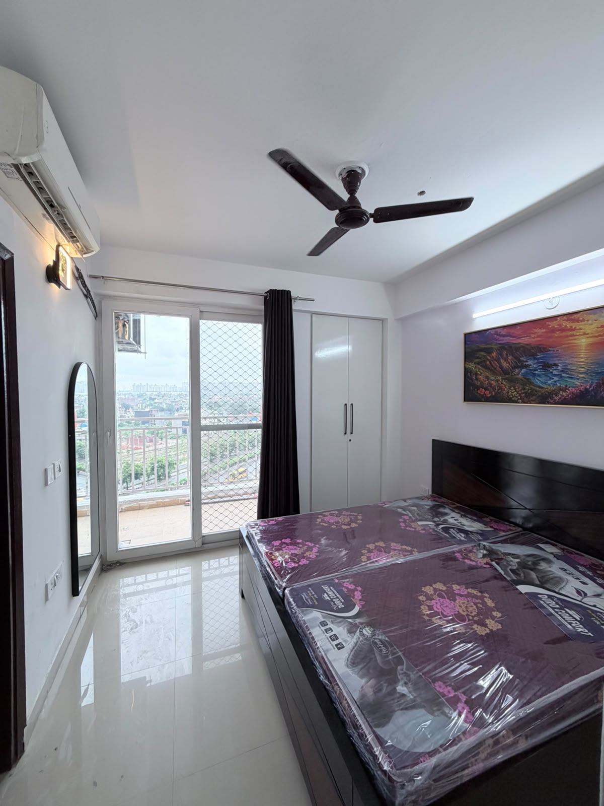 Same bedroom furnished with a bed, mirror, and wall decor after Eastern Yard furnishing